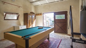 Une table de billard dans une pièce dotée d’un tapis à motifs, d’une armoire et d’une porte donnant sur l’extérieur.