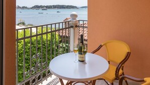 A balcony with a round table and two chairs, overlooking a body of water with boats and a distant shoreline. - Apartment Fiorido Brown a2 (Medulin)