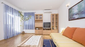 Un salon comprenant un canapé, une table basse, un téléviseur et un meuble.