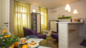 Een moderne woonkamer met een ontbijt klaargemaakte eettafel, een keukenhoek met een magnetron en een in de muur geïntegreerde, metselwerk schoorsteen.