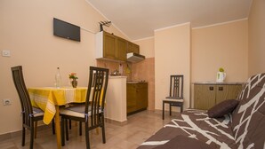 A compact living space with a dining area, kitchenette, and a sofa.