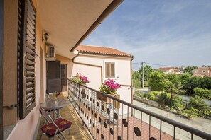 A balcony with a table and chairs, a small potted plant, and a view of a residential area. - Apartment Marija Valtura / One Bedroom (Liznjan)
