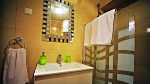 A bathroom with a sink, mirror, towel rack, and shower area. - Studio Erika (Rovinj)