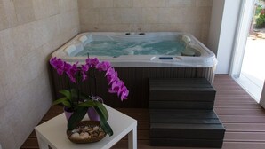 A spa area with a hot tub, a small table with a potted orchid, and wooden steps. - Istrian Villa Lavanda (Kanfanar)