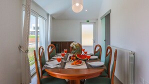 A dining area with a round table set for four, surrounded by chairs. There are plates, cutlery, and glasses on the table, along with a fruit platter and a vase with flowers. - Istrian Villa Lavanda (Kanfanar)