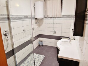 Une salle de bain avec douche, toilettes et lavabo.