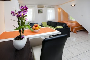 Relax in a cozy living area with a comfortable sofa, dining table for two, and a stylish bed.