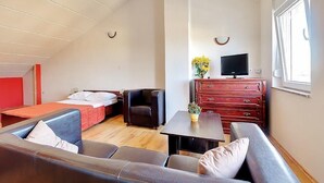 Un espace de vie compact comprenant un canapé, une petite table, un téléviseur et une commode.