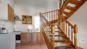 Une cuisine avec des meubles de rangement en bois, une cuisinière encastrée et un escalier en bois menant à un autre niveau.
