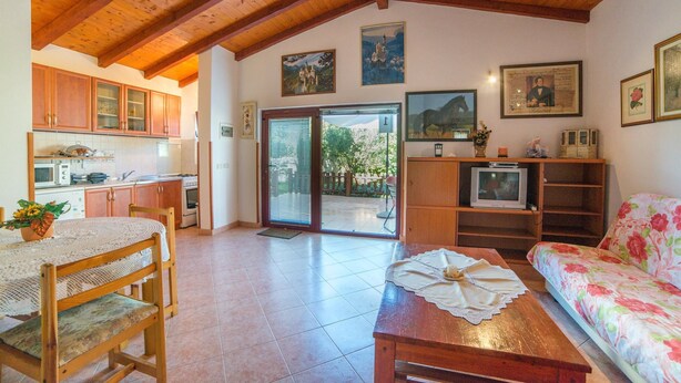 A cozy living room with wooden furniture, a dining table with a lace tablecloth, and a sofa with floral upholstery. - Apartment Nada / One Bedroom (Rovinj)