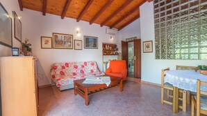 A cozy living room with a wooden ceiling, a floral sofa, a wooden coffee table, and a dining table with chairs. - Apartment Nada / One Bedroom (Rovinj)
