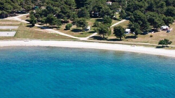 An aerial view of a coastal area with a beach, clear blue water, and scattered trees. - Apartment Andrea / Galery one Bedroom (Vodnjan)