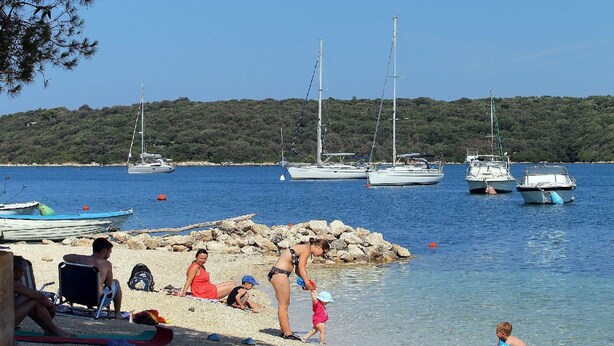 A beach with boats, people, and a clear sky.
