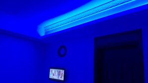 A room with a dark door, a small circular object on the wall, and a television screen. - Wasafi Garden & Spa Kibiko (Nairobi)