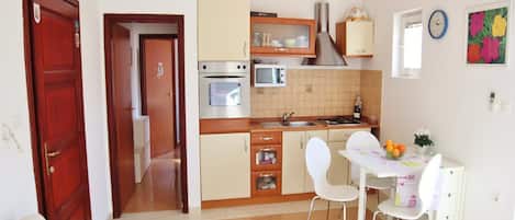 Une cuisine compacte équipée d’une cuisinière, d’un four à micro-ondes et de placards. Un coin repas avec une table et des chaises est également disponible.