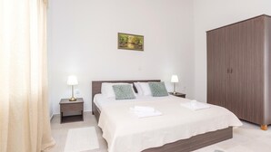 Um quarto bem arrumado com uma cama, mesas de cabeceira, um guarda-roupa e um quadro na parede.