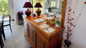 A kitchen with a wooden counter, two lamps, a vase with dried plants, and a large mirror.