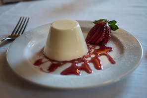 A dessert plate with a panna cotta, strawberry, and sauce. - Ristorante Albergo Arcade (Grandate)