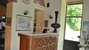 A reception desk with a framed landscape painting, a clock, and a window with a view of greenery. - Ristorante Albergo Arcade (Grandate)