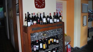 A wine rack with multiple bottles and glasses, a clock, and a fire extinguisher. - Ristorante Albergo Arcade (Grandate)