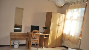A bedroom with a bed, a desk, a chair, a wardrobe, and a window with curtains. - Ristorante Albergo Arcade (Grandate)