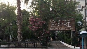Señal del Restaurante Hotel D.C. Phine, rodeado de árboles y un banco.