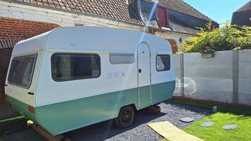 A vintage camper parked in a driveway with a house in the background.