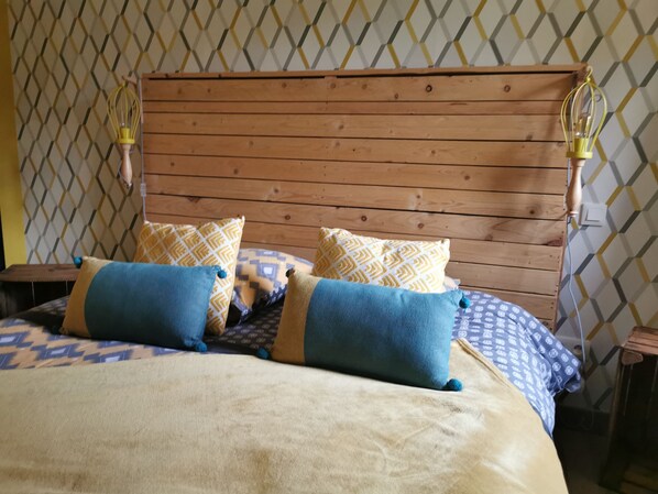 A bed with a wooden headboard, patterned pillows, and a blanket.