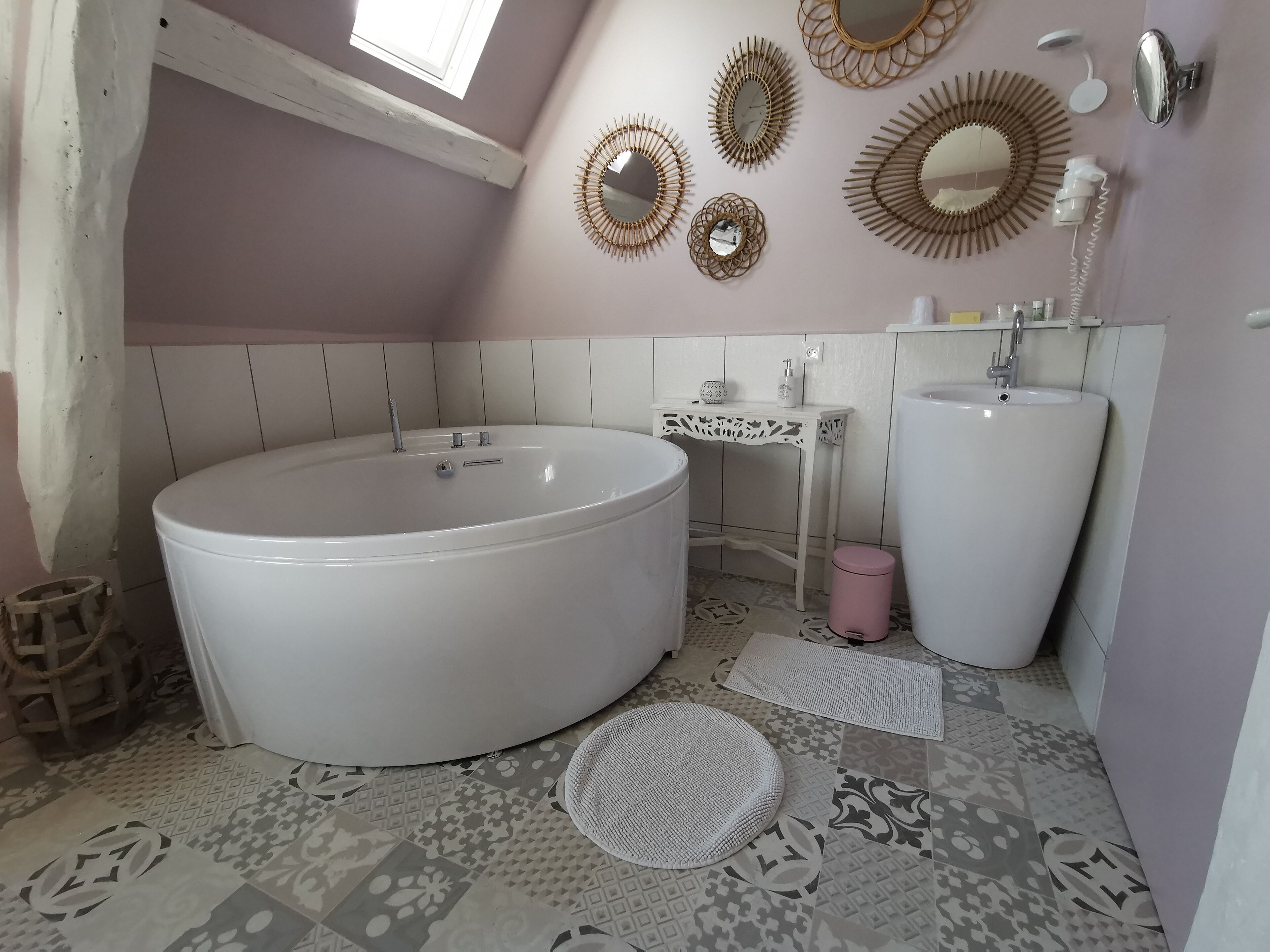 Een badkamer met een groot bad, een wastafel en decoratieve spiegels aan de muur.
