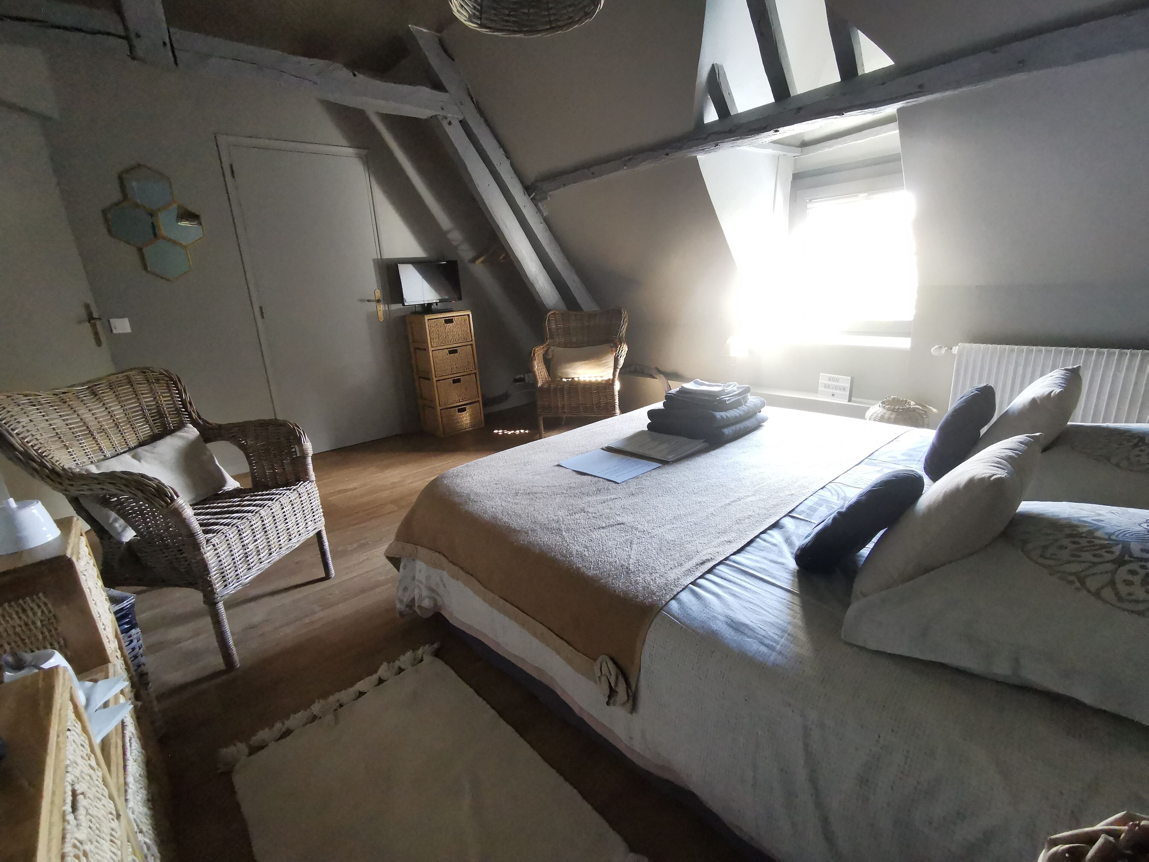 Een slaapkamer met een bed, een stoel, een dressoir, een raam en een radiator.