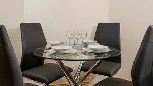 Ett matbord med fyra svarta läderstolar, genomskinliga glas och vita tallrikar, dukat för fyra personer.