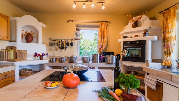 A kitchen with a central island, a stove, and various kitchen utensils. - Ostsee Ferienhaus Welzin - Schulgartenhaus (Damshagen)