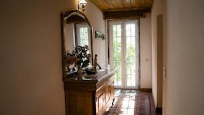A hallway with a wooden cabinet, a mirror, and a door leading outside.