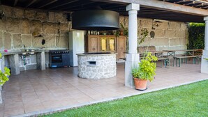 An outdoor kitchen area with stone walls, a stone oven, and a large black grill.