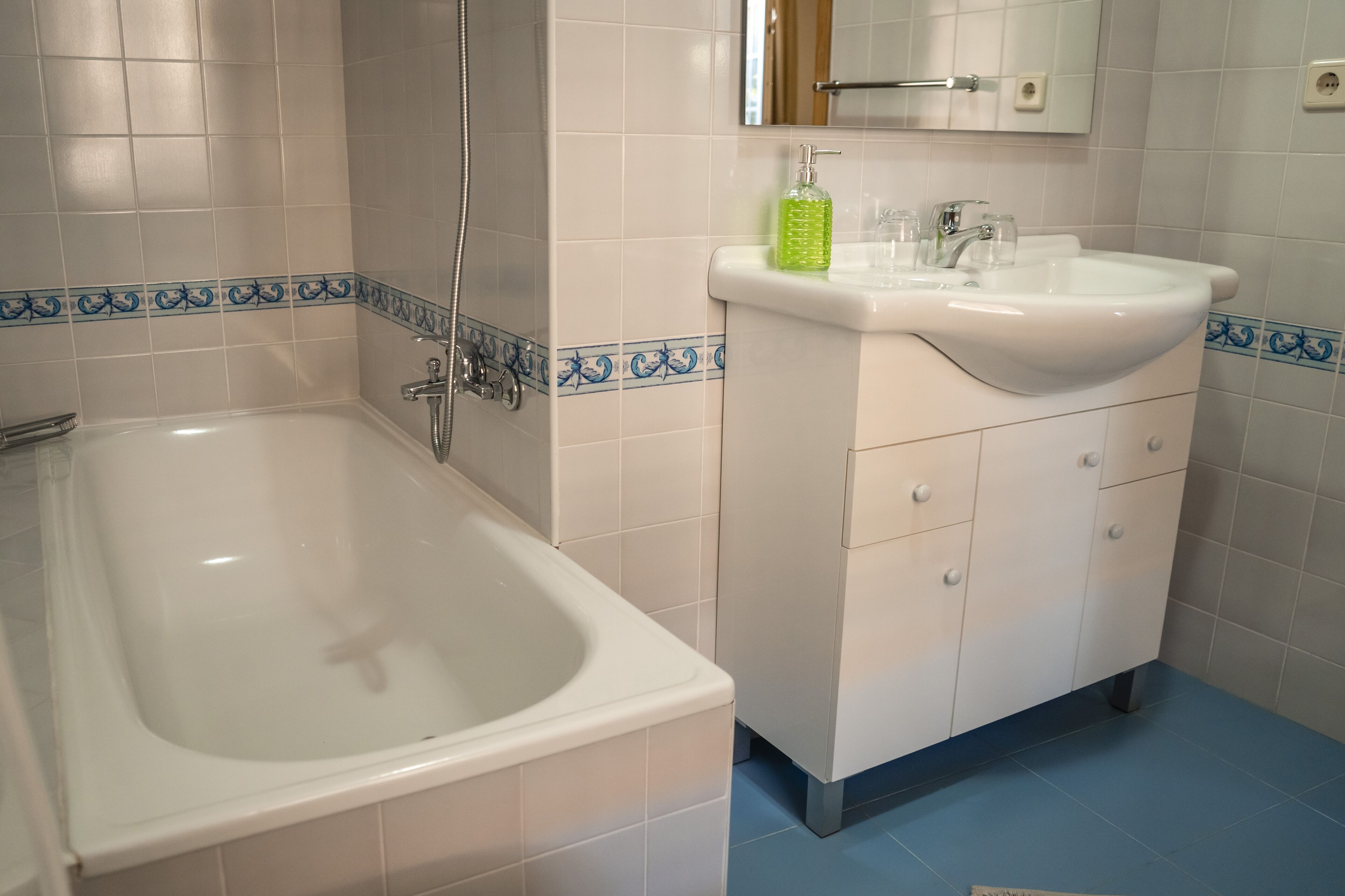 A bathroom with a bathtub, a sink, and a mirror.