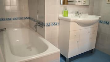 A bathroom with a bathtub, a sink, and a mirror.