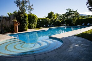 Une piscine à l’eau d’un bleu cristallin, entourée d’une terrasse dallée et de chaises longues.