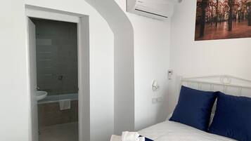 Un dormitorio con cama, baño y un cuadro en la pared.