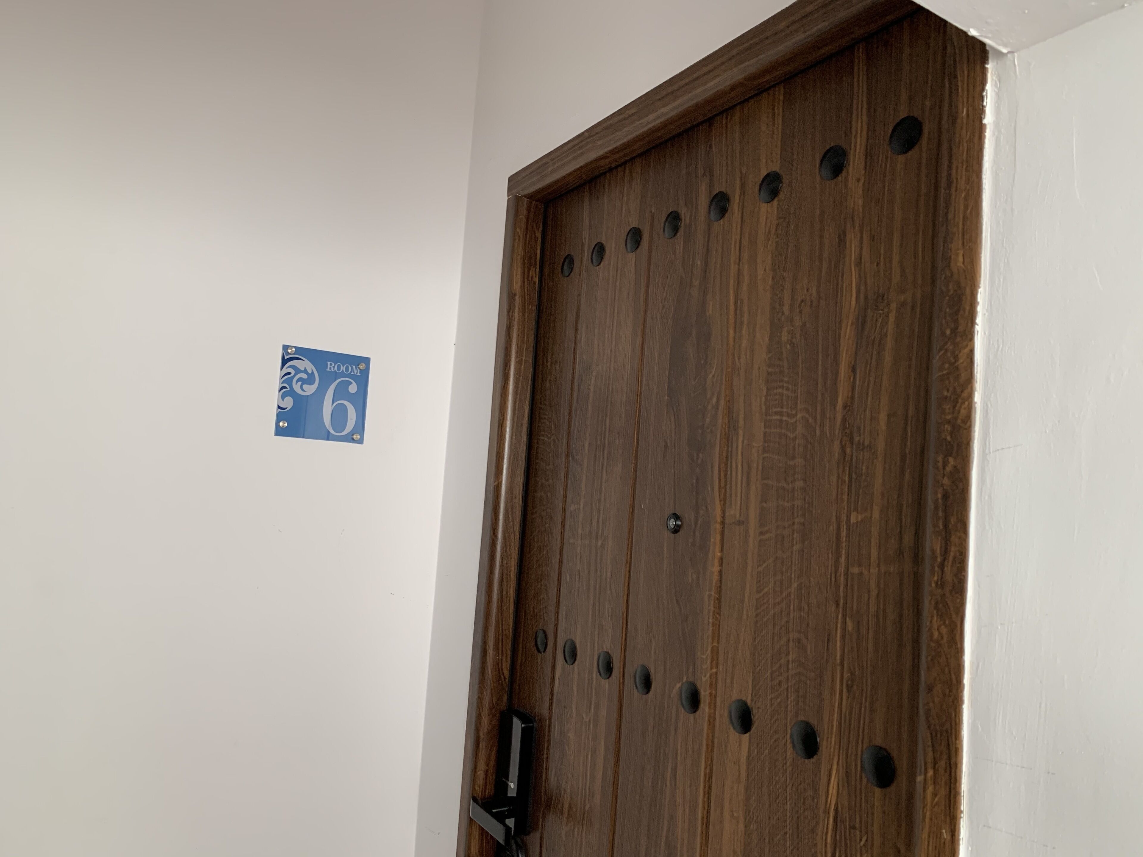 Una puerta de madera con un cartel que indica la habitación número 6.