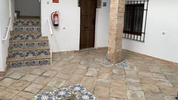 Una escalera con baldosas estampadas que conduce a una entrada, un extintor y una puerta con un pilar de piedra.