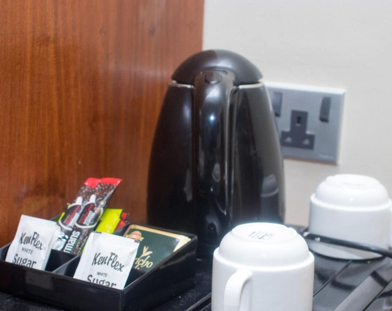 Een koffiezetapparaat, een koffiekan en een dienblad met koffiepads en suikerzakjes.