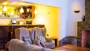 Hyggelig opholdsstue med bar, sofaer og pejs.