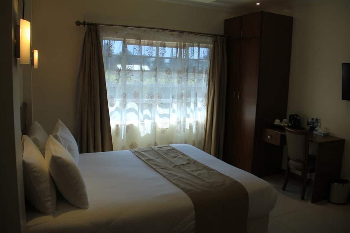A hotel room with a large bed, a desk, and a wardrobe.
