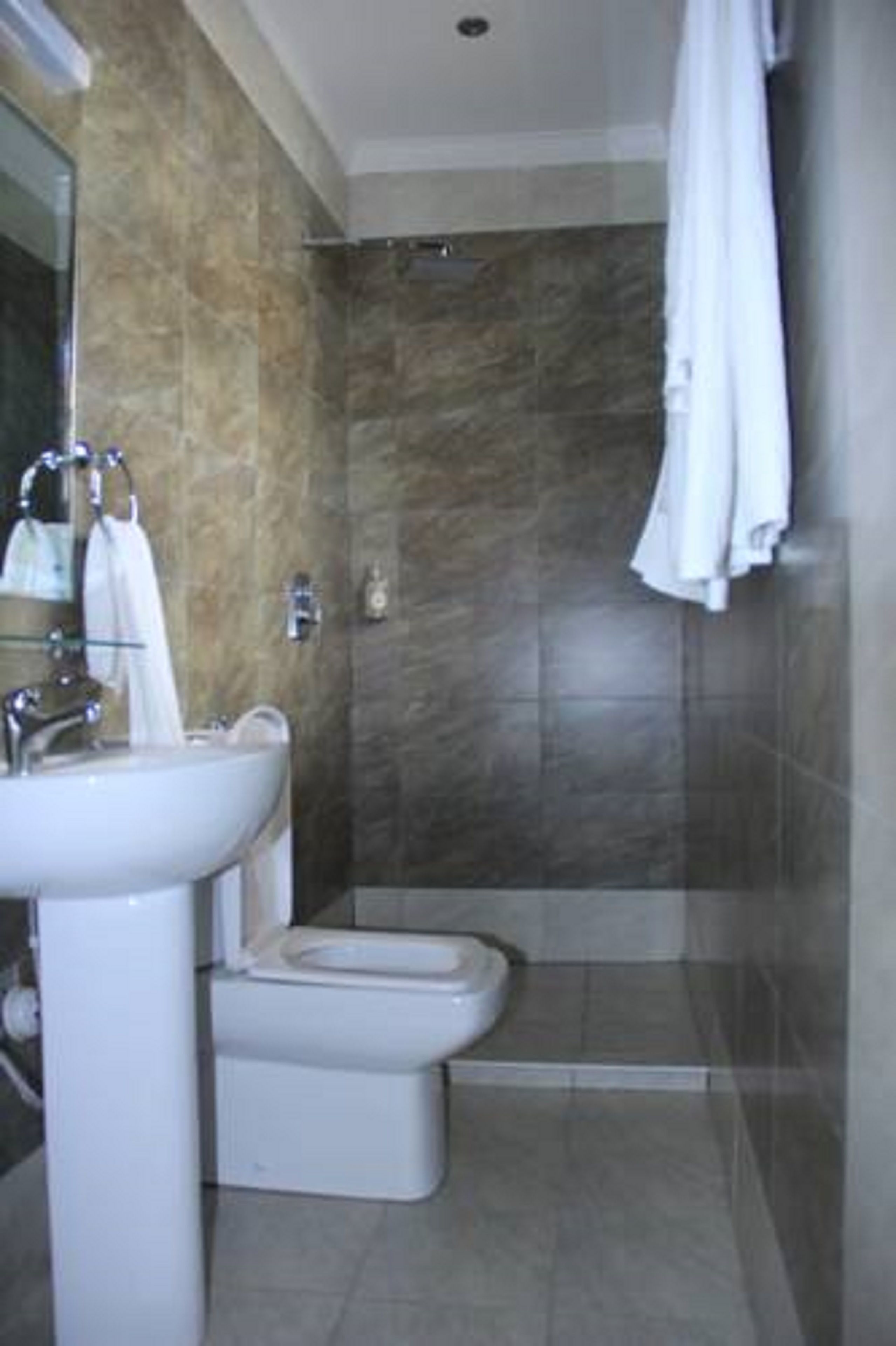 A bathroom with a sink, toilet, and shower area.