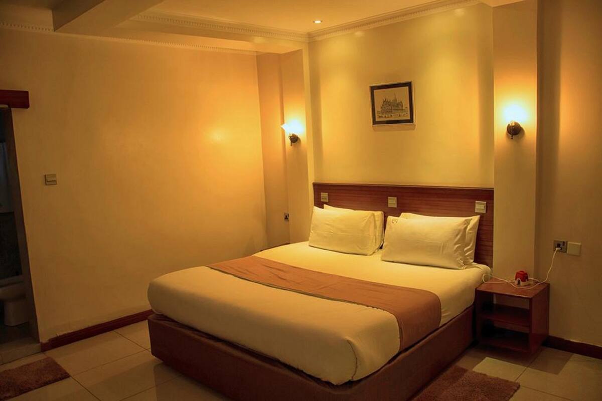 A hotel room with a large bed, a wooden headboard, two bedside tables, and a framed picture on the wall.