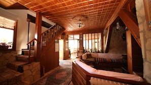 Un interior acogedor con una escalera de madera, una pared de piedra, una cama con almohada a rayas y vistas al exterior.