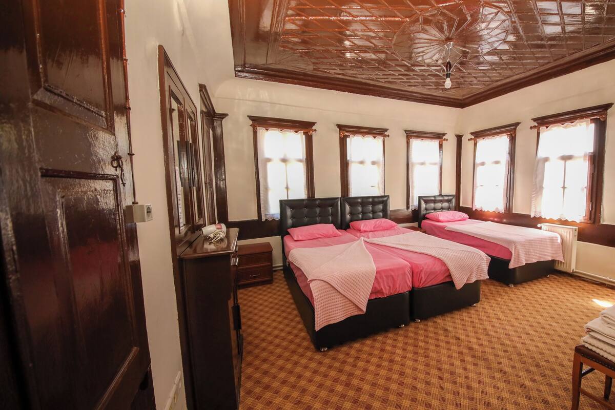 Une chambre avec deux lits, un plafond en bois et un tapis à motifs.