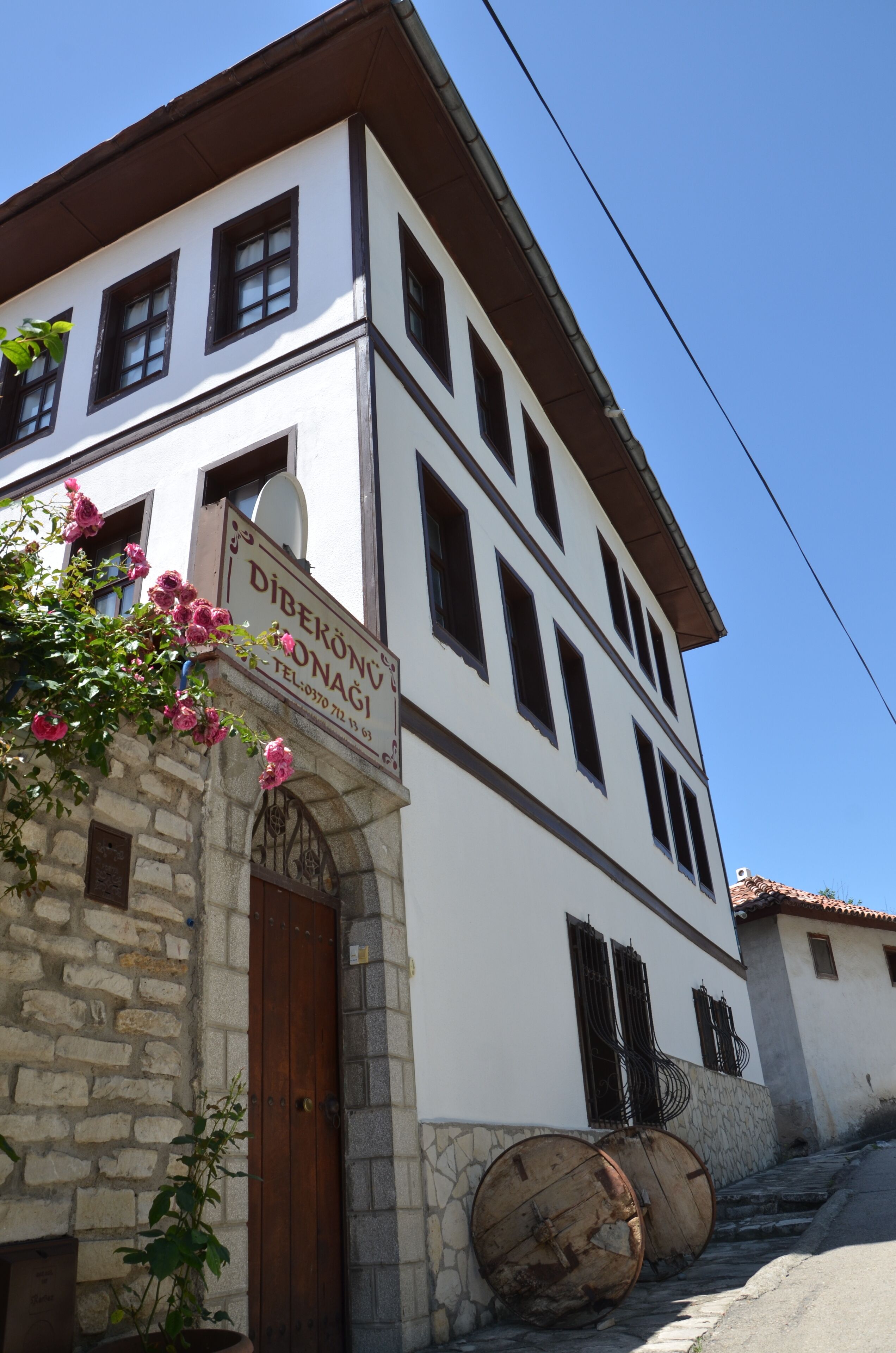 Un edificio de dos pisos con base de piedra y paredes superiores blancas, que presenta un letrero con el nombre 