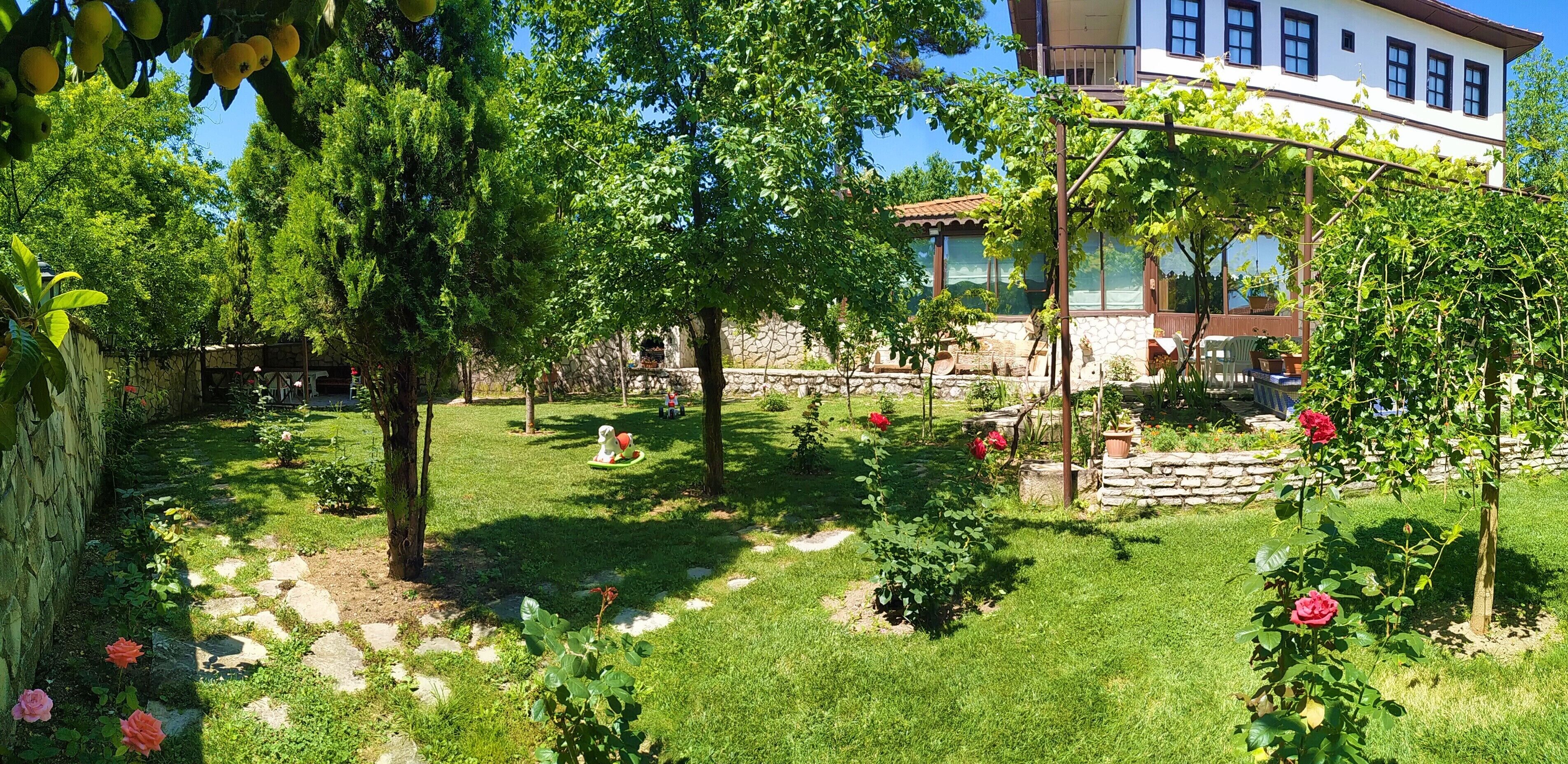 A garden with a stone wall, a gazebo, and a building with multiple windows.