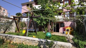 A residential building with a balcony, a swing set, and a small play area with a slide and a ball pit. - Apartments Margareta (Pula)